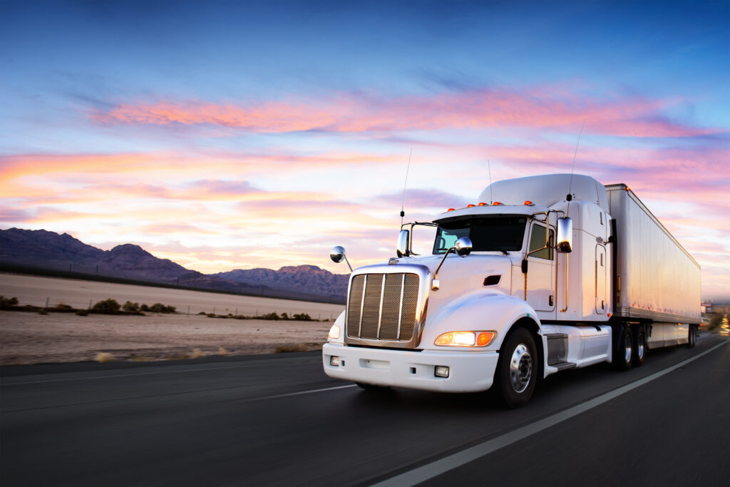 Semi truck driving down the freeway at sunset