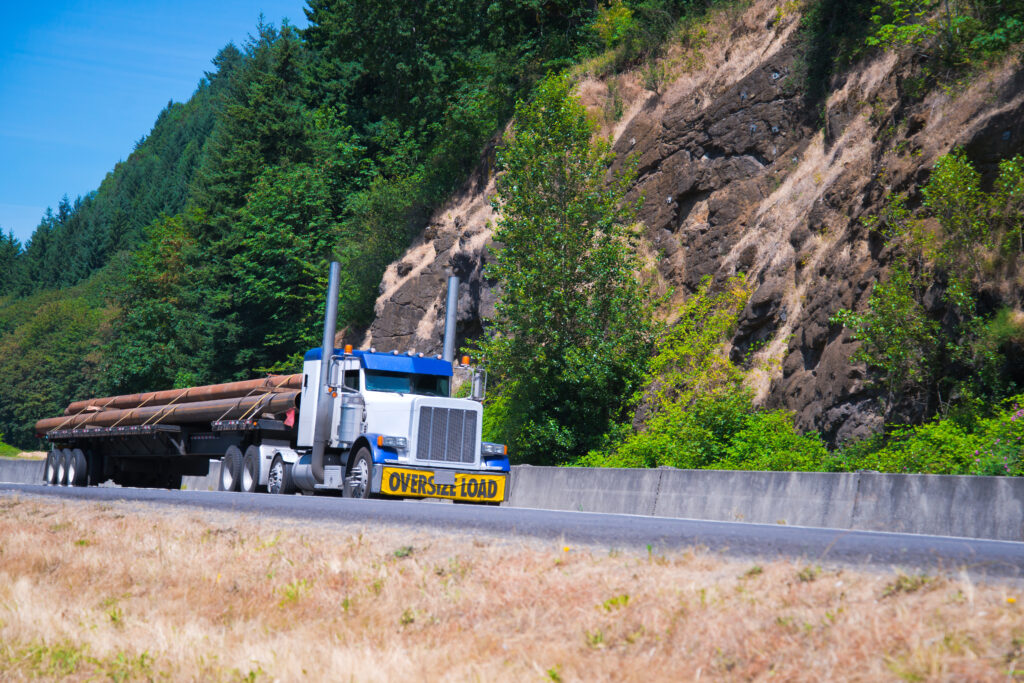 Modern semi truck with high exhaust pipes transporting oversized load